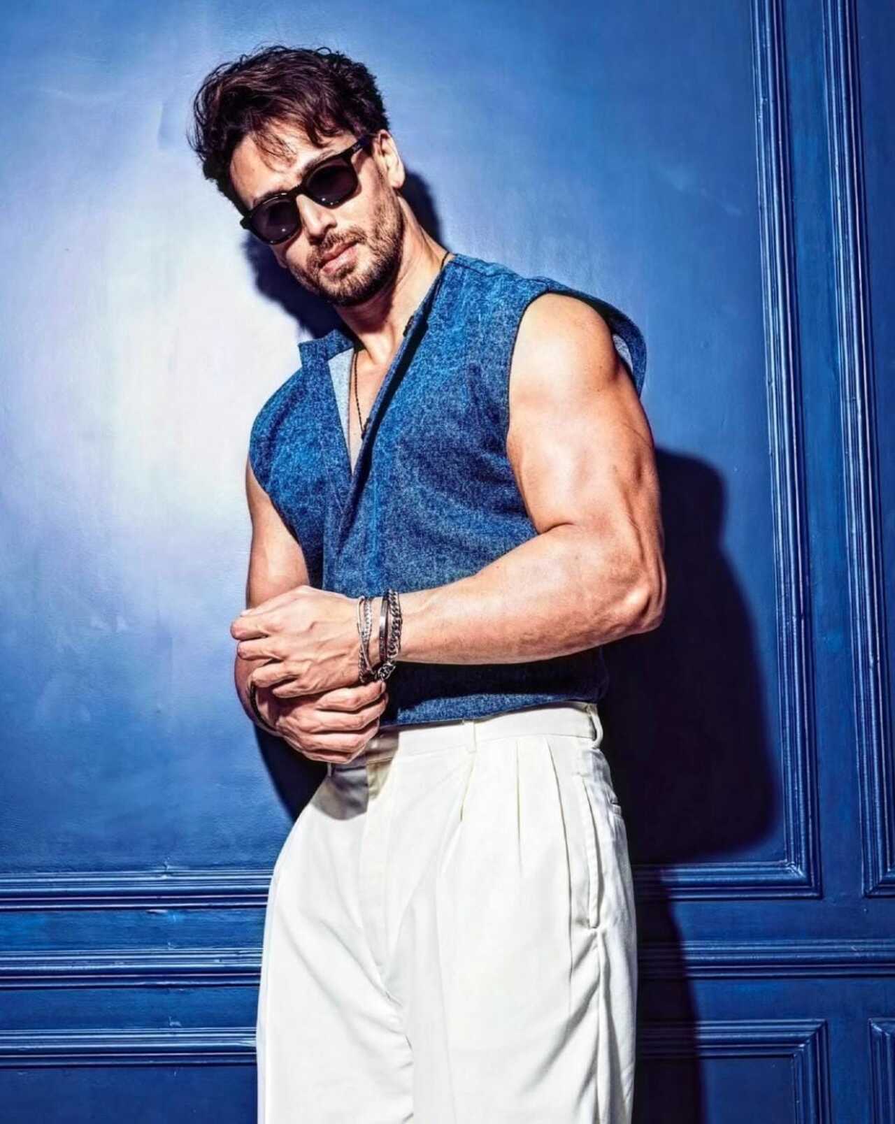 In a textured blue sleeveless shirt, pristine white wide-leg trousers, and dark square sunglasses, Tiger channels effortless Mediterranean cool.